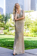 A woman poses for the camera, wearing a stylish champagne-colored dress that highlights her graceful presence.