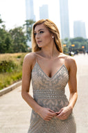 A blonde woman in a fashionable dress poses for the camera, exuding beauty and confidence in her expression.