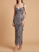A woman models a midi-length gray lace dress with a floral pattern and thin shoulder straps against a solid beige studio background.
