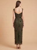 A woman viewed from the back wearing a sleeveless, midi-length olive green lace dress with a deep V back and fitted silhouette, standing against a warm beige studio backdrop.