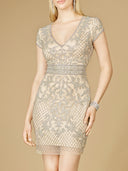 A woman wears the Lara 29571 Embellished Short Dress featuring a V-neck, cap sleeves, silver sequins, and a fitted waist, standing against a plain beige background.