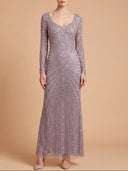 A woman modeling a floor-length lavender-gray gown with long sleeves, a scoop neckline, and intricate beaded sequin detailing arranged in a sunburst pattern on a warm beige studio background.