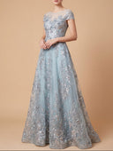 Woman wearing a silver evening gown with floral embroidery on a beige background