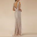 Woman wearing a long, elegant dress with a white and silver beaded pattern on a white background