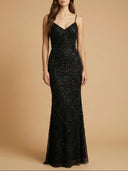Woman wearing a black sequin evening gown against a beige background