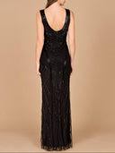 A woman with long brown hair faces away, wearing the Lara 33552— a sleeveless, floor-length black fitted dress with tonal beading and a low scoop back. The background is plain beige.
