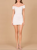 A model wearing a white, beaded off-shoulder bridal cocktail dress with a sweetheart neckline and a low lace-up back.