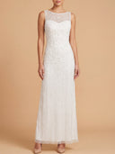 A woman modeling a sleeveless white lace and bead maxi dress with a sheer round neckline, standing against a solid beige studio background.