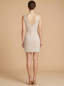 A woman shown from the back wearing a sleeveless, off-white lace mini dress with a deep V-neckline and a buttoned back, set against a solid beige studio background.