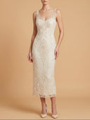 A woman modeling a sleeveless lace midi dress in warm ivory against a solid beige studio background.