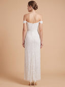 A woman shown from the back wearing an off-the-shoulder white lace wedding gown with a fitted bodice and floor-length skirt, standing against a warm beige studio background.